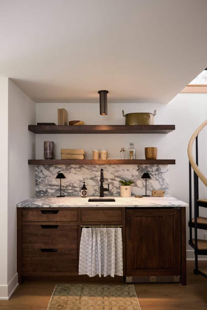 A gorgeous marble countertop set against walnut wood cabinets, featuring a Precious Metals Reveler sink in Gunmetal