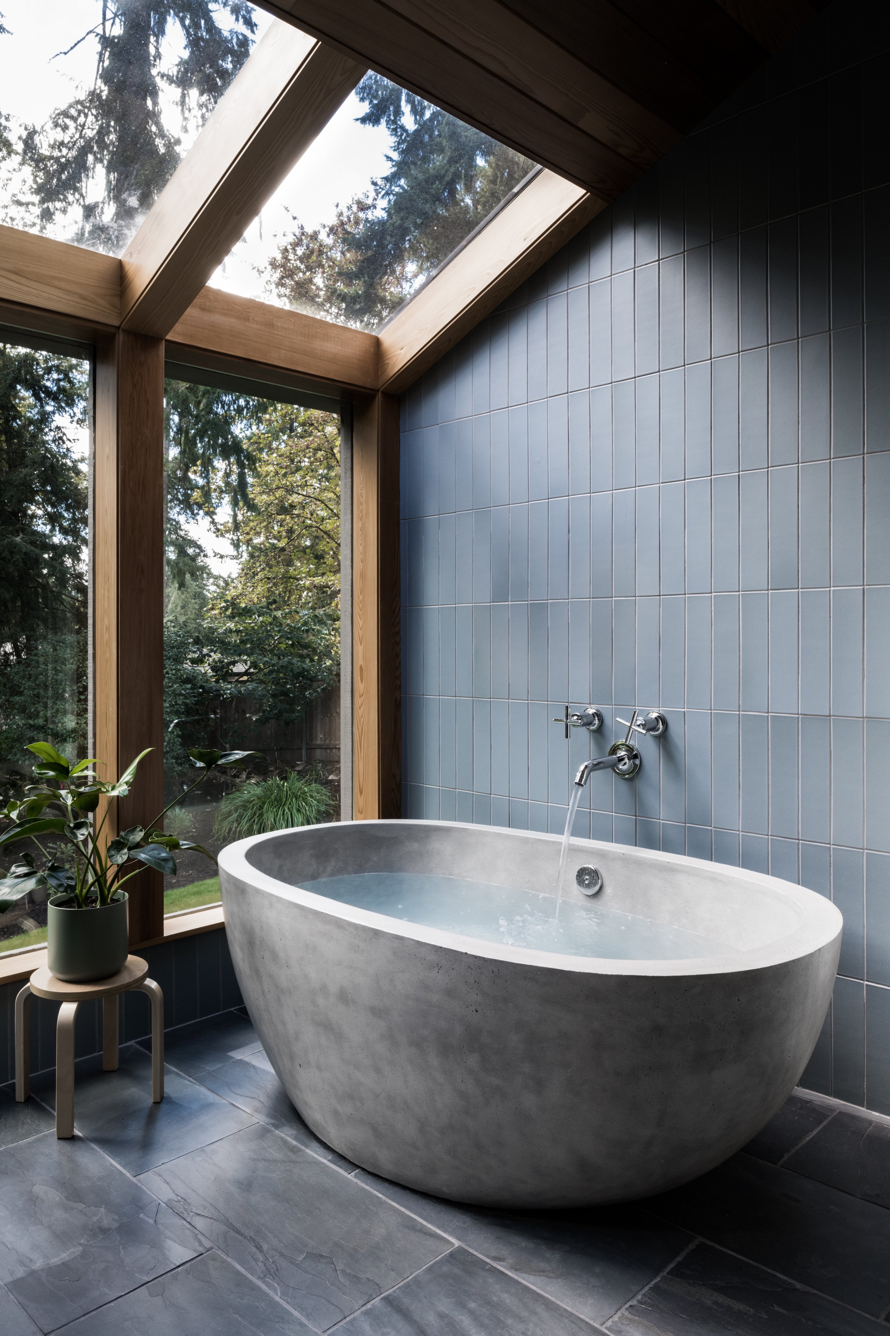 Mid-century modern design atrium style bathroom with floor to ceiling windows, floor to ceiling ceramic tile and a NativeStone concrete bathtub