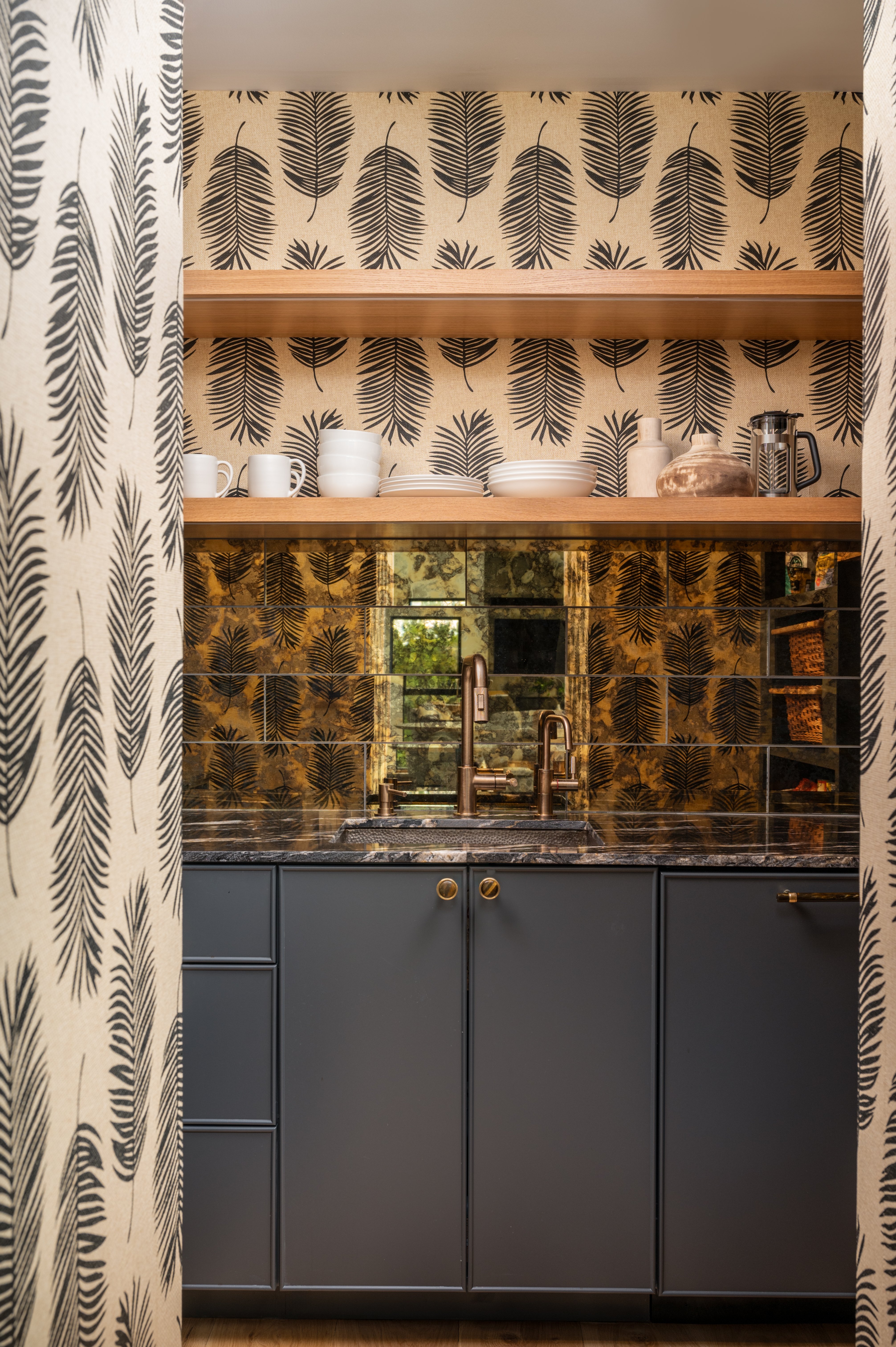 Copper bar sink with brushed nickel finish set against a vibrant colored wallpaper and mirrored wall