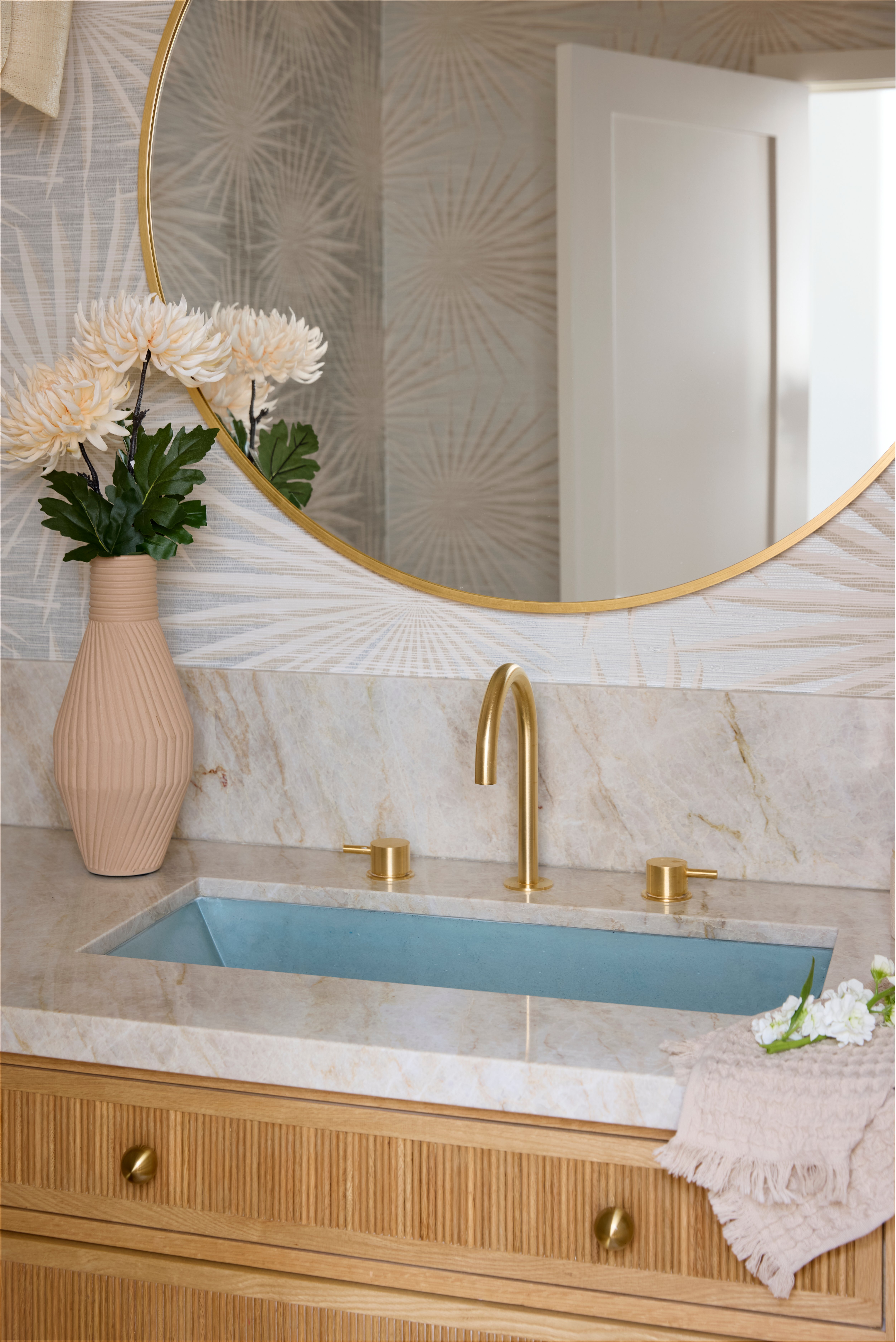 Blue concrete bathroom sink in powder room with gold bathroom faucet and vibrant tropical wallpaper