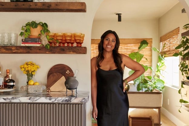Interior Designer to celebrities, Hema Persad, poses in a relaxed manner next to a kitchen she's designed, which features a marble countertop.