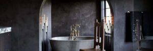 A moody, bathroom sanctuary with dramatic candelabras and a charcoal NativeStone concrete bathtub.