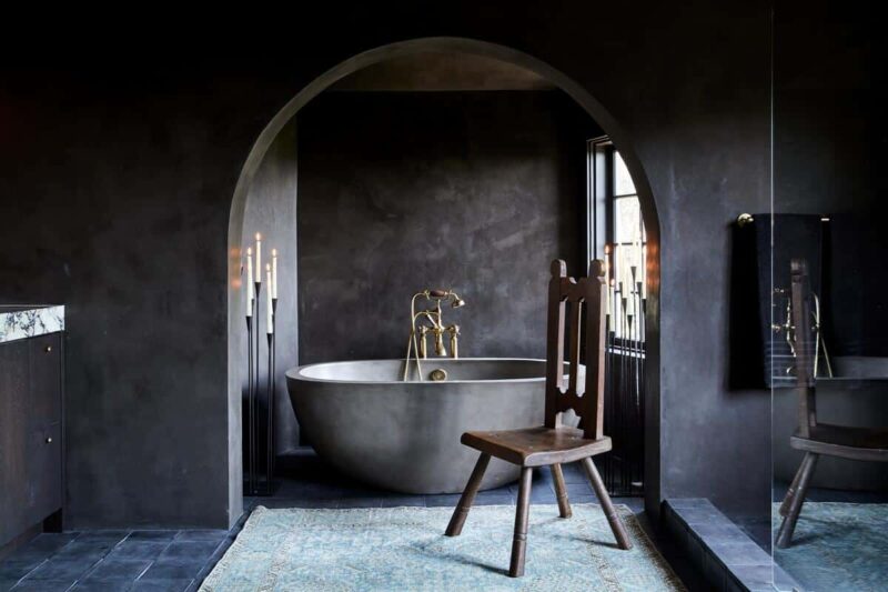A moody, bathroom sanctuary with dramatic candelabras and a charcoal NativeStone concrete bathtub.