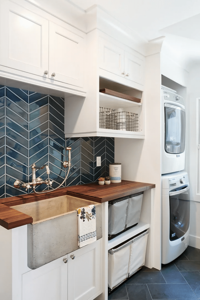 Native Trails sinks used in a bespoke laundry space feature a NativeStone concrete sink in Ash and a vibrant blue herringbone tile backsplash.